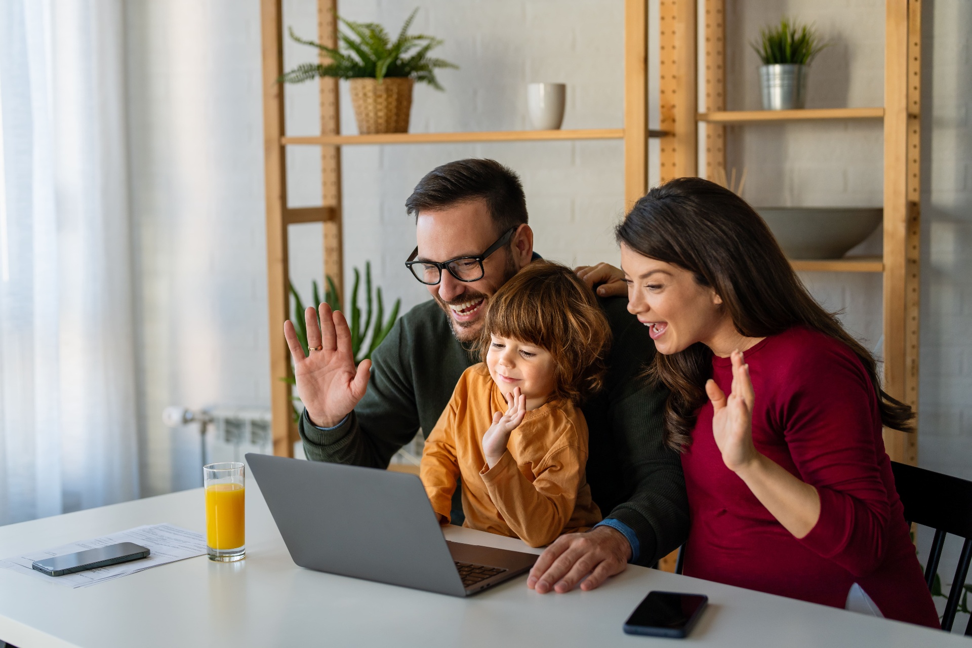 Family waving at laptop during virtual healthcare visit